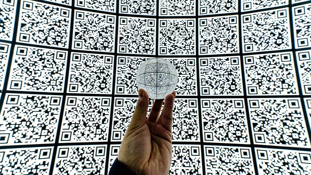 Image of a hand holding a glass ball with a background of qr codes