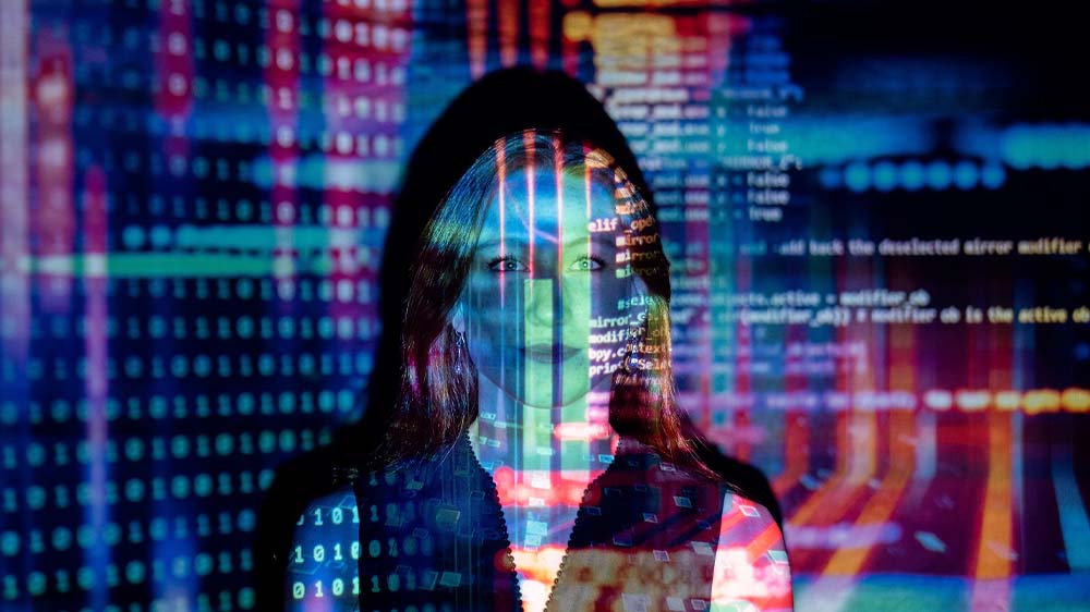 Photo of a woman with binary code reflecting across her face, illustrating technology